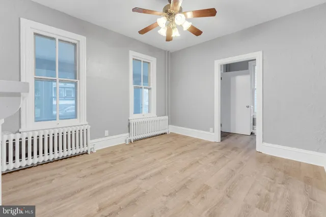 a view of an empty room with a window and a chandelier fan