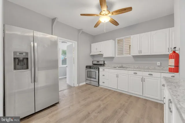 a kitchen with granite countertop a refrigerator a sink and white cabinets