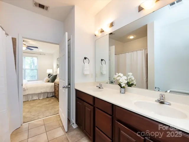 a en suite bathroom with a double vanity sink a mirror and a bathtub