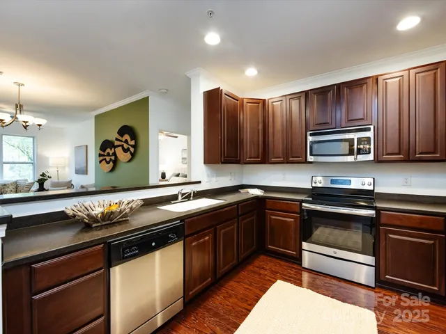 a kitchen with stainless steel appliances granite countertop wooden cabinets a stove a sink and a microwave
