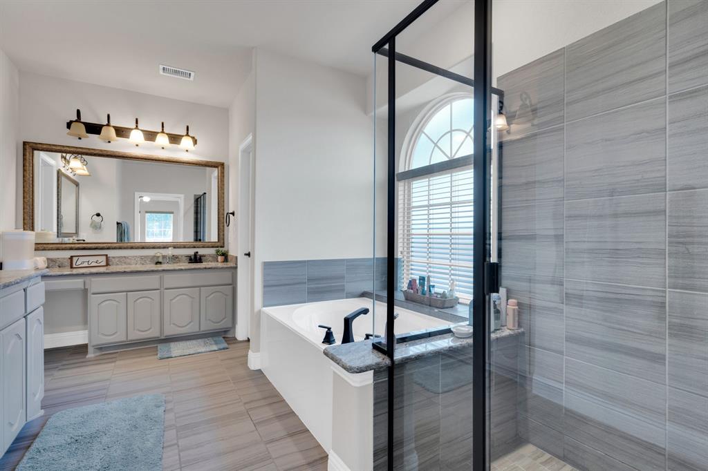 129 Micco Lane Fate, TX 75087 - Photo 11 of 31 a bathroom with a granite countertop sink mirror and a bathtub