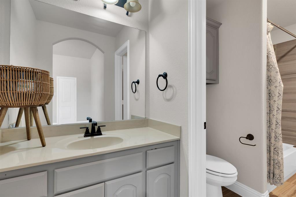 129 Micco Lane Fate, TX 75087 - Photo 18 of 31 a bathroom with a sink a toilet and a mirror