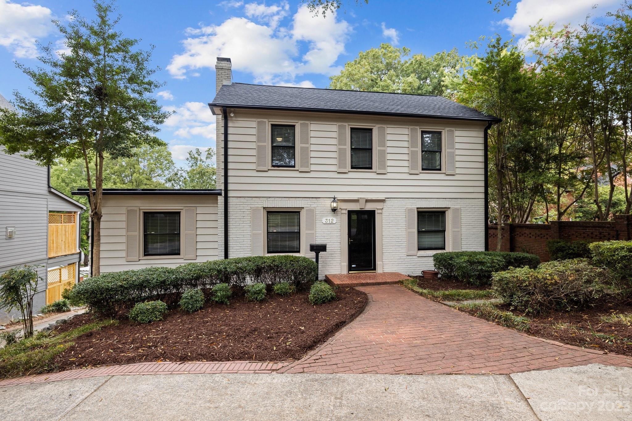 312 Brandywine Road Charlotte, NC 28209 - Photo 3 of 31 a white house with a small yard plants and large trees