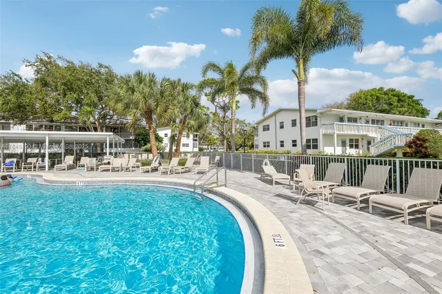 a view of a swimming pool with a lounge chair and palm trees