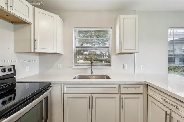 a kitchen with stainless steel appliances granite countertop a sink a window and a white cabinets