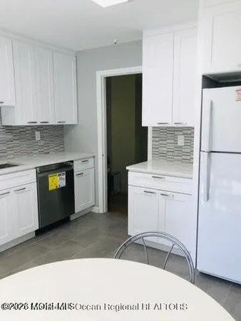 a kitchen with a refrigerator and white cabinets