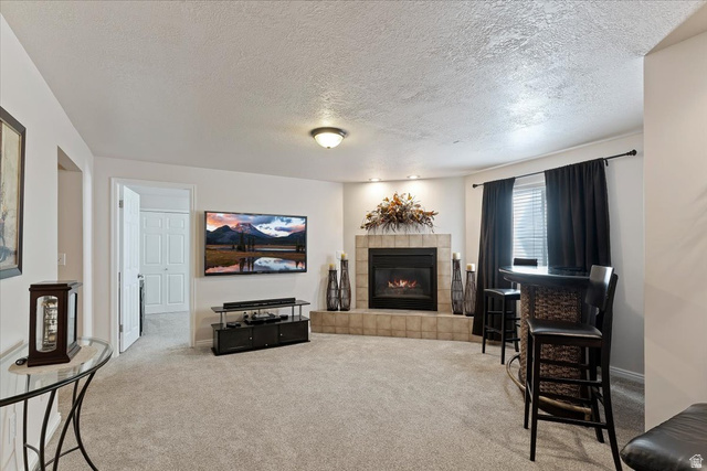 1924 North 2000th Street East Layton, UT 84040 - Photo 28 of 41 Carpeted living area featuring a textured ceiling and a tiled fireplace