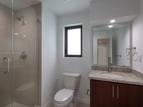 a bathroom with a granite countertop sink a toilet and shower