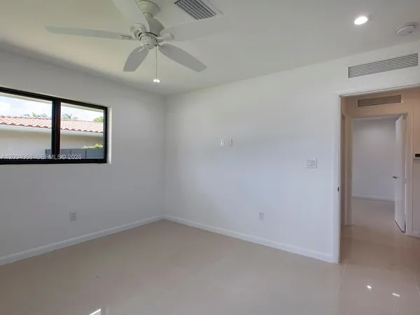 an empty room with windows and fan