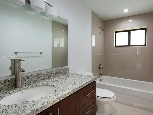 a bathroom with a granite countertop sink a toilet and bathtub