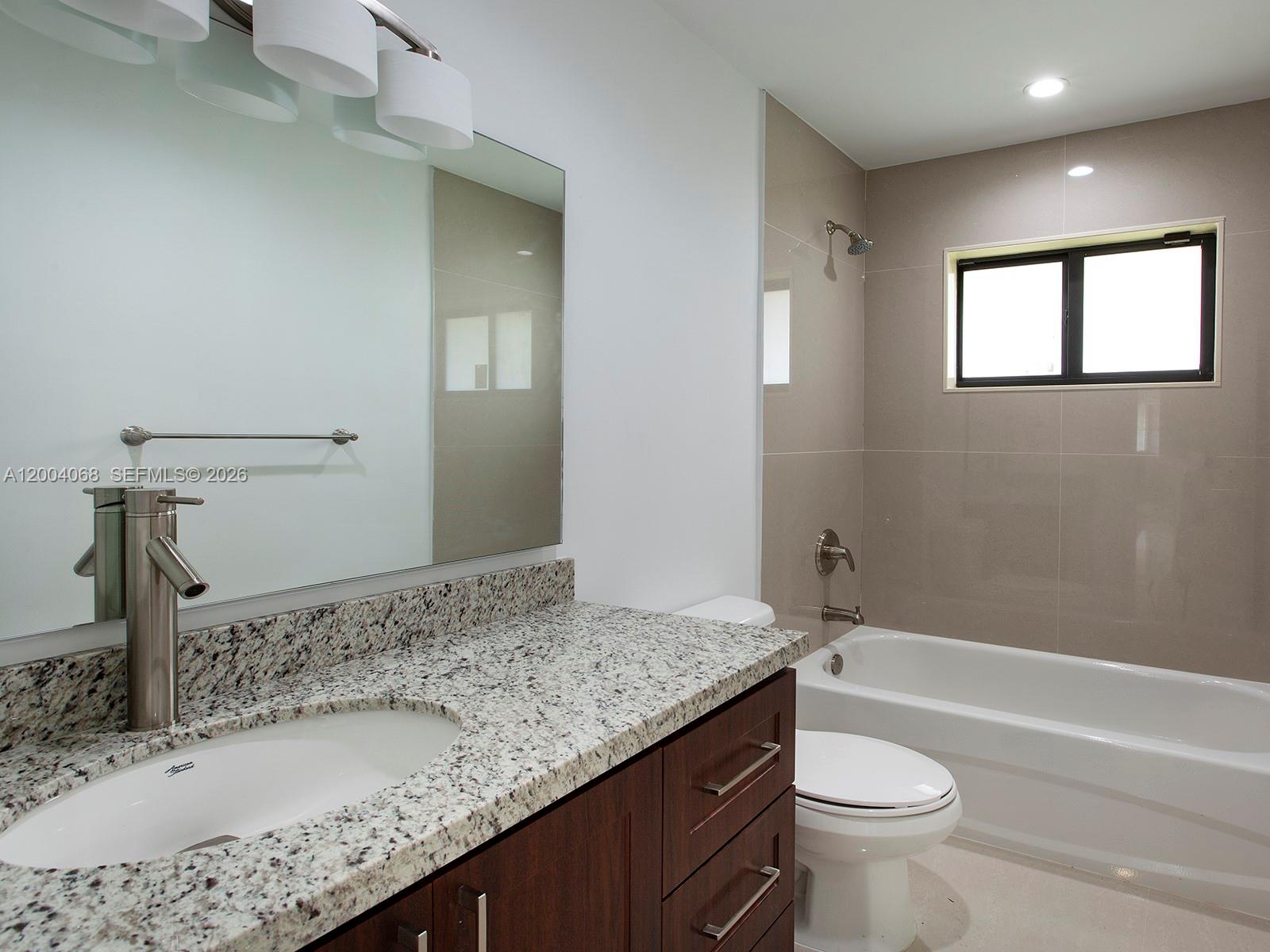 8790 Southwest 85th Street Miami, FL 33173 - Photo 18 of 20 a bathroom with a granite countertop sink a toilet and bathtub