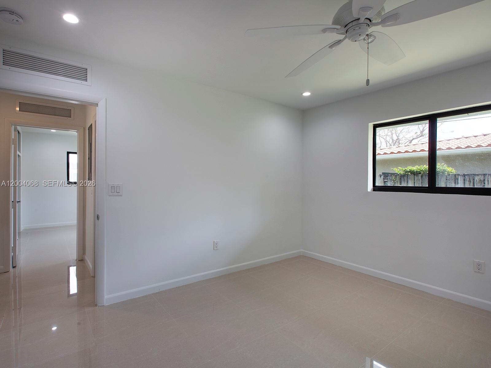 8790 Southwest 85th Street Miami, FL 33173 - Photo 20 of 20 an empty room with a window and a chandelier fan