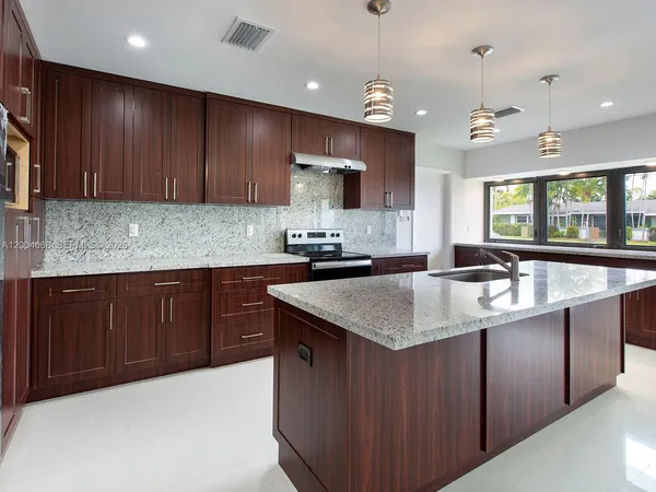 a kitchen with granite countertop a sink a counter top space appliances and cabinets
