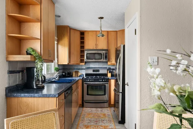a kitchen with stainless steel appliances granite countertop a stove refrigerator and a sink