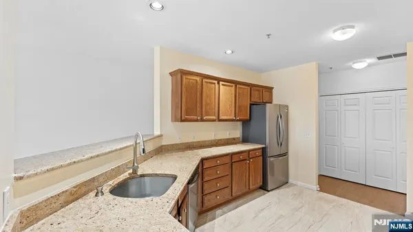 a kitchen with stainless steel appliances granite countertop a sink refrigerator and cabinets