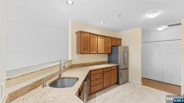 a kitchen with stainless steel appliances granite countertop a sink refrigerator and cabinets