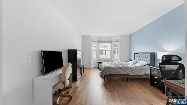 a bedroom with a bed and a flat tv screen on a dresser