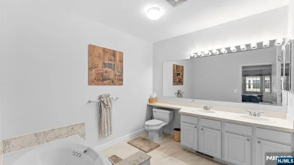 a bathroom with a double vanity sink toilet mirror and bathtub