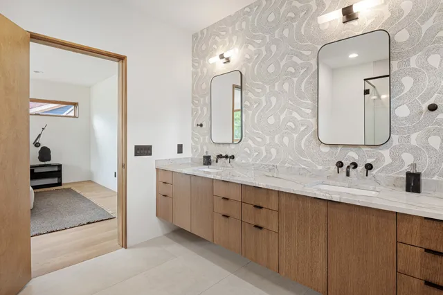 a bathroom with double vanity sinks a toilet a mirror and shower