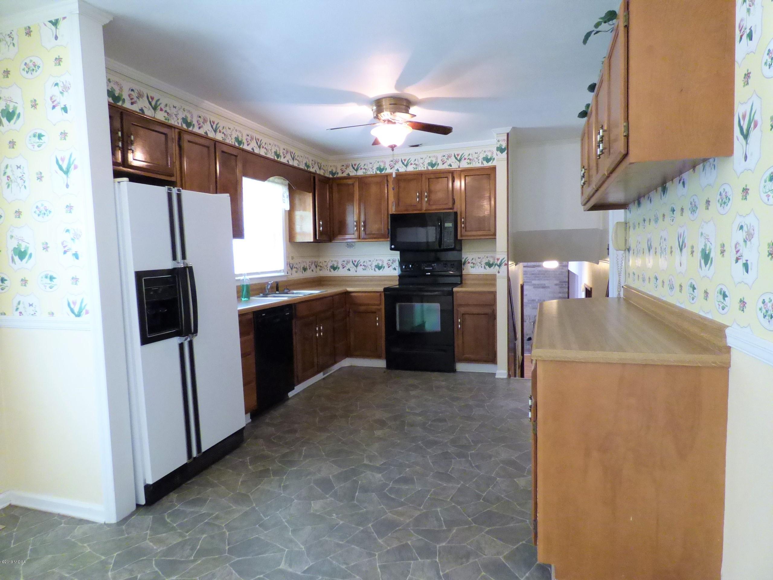6898 Columbus Road Lizella, GA 31052 - Photo 8 of 22 a kitchen with stainless steel appliances granite countertop a sink stove and refrigerator