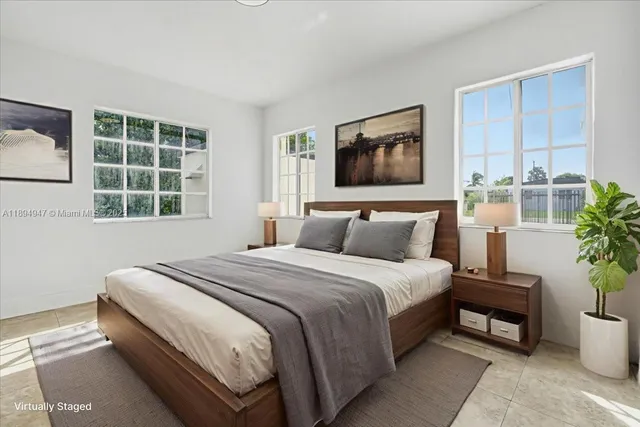 a bedroom with bed a potted plant and a window
