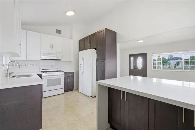 a kitchen with a white appliances a sink and a refrigerator