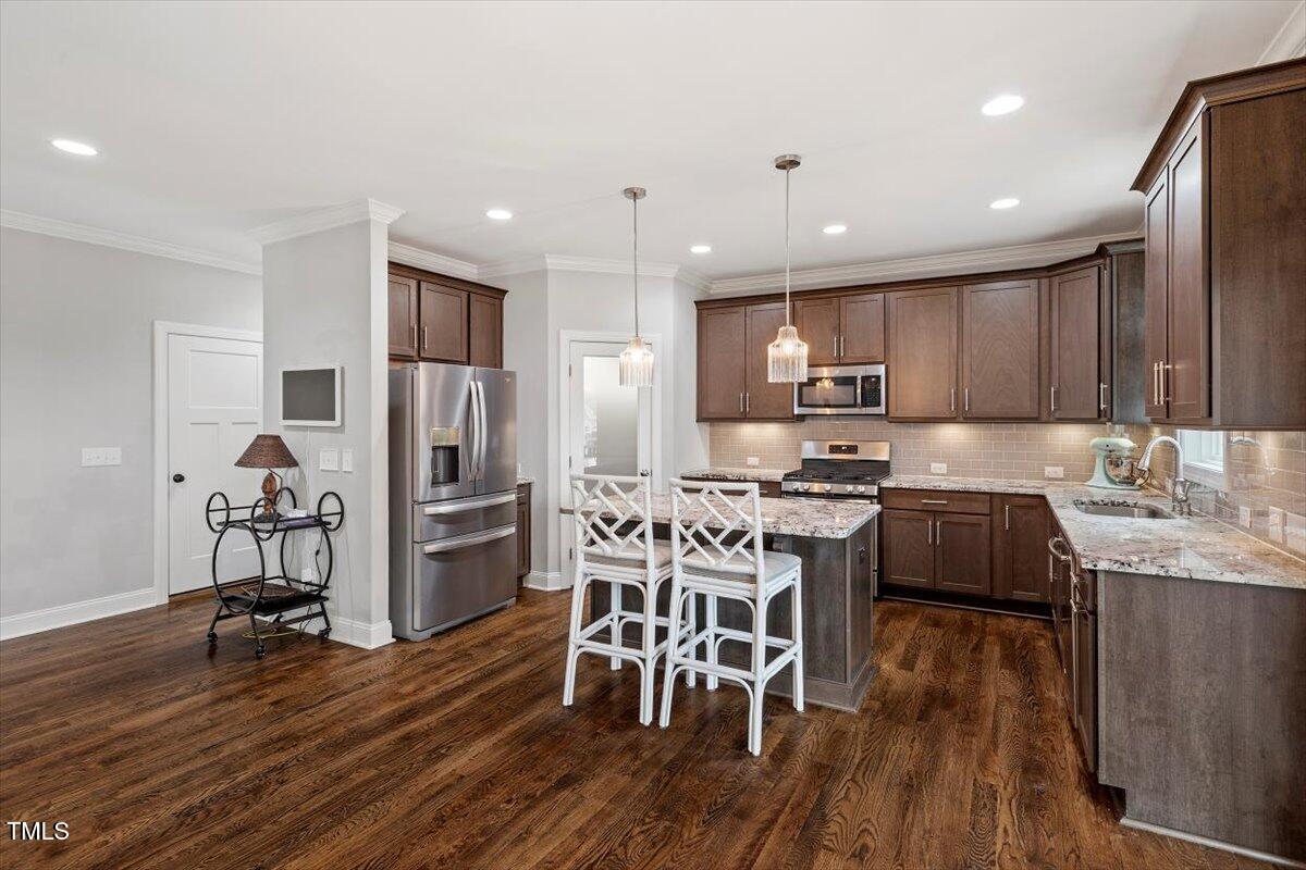 357 Marshcroft Way Rolesville, NC 27571 - Photo 12 of 41 a kitchen with stainless steel appliances granite countertop a stove top oven a sink a refrigerator white cabinets and wooden floor