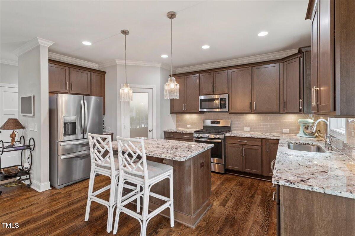357 Marshcroft Way Rolesville, NC 27571 - Photo 13 of 41 a kitchen with stainless steel appliances granite countertop wooden floors a stove a sink and a refrigerator