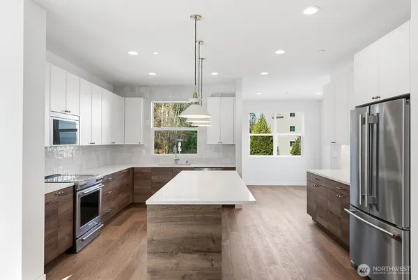 a large kitchen with stainless steel appliances granite countertop a stove a sink and a refrigerator
