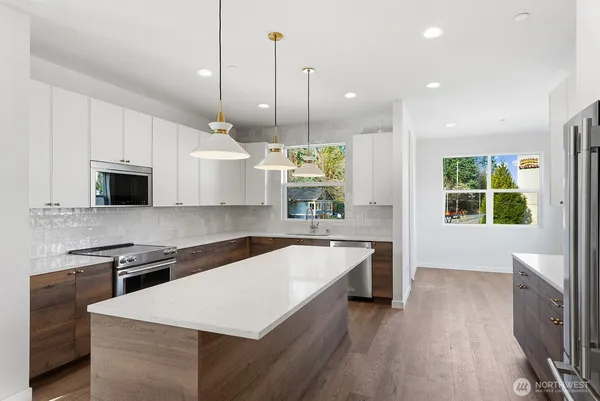 a large kitchen with stainless steel appliances a large center island attached withe living room