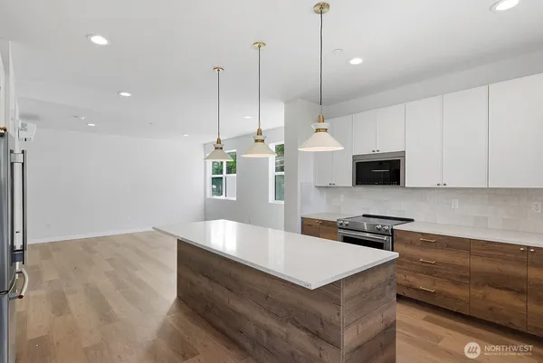 a kitchen with stainless steel appliances granite countertop a sink a microwave a stove and a white cabinets
