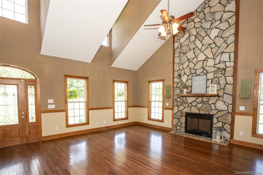 122 Barrier Farms Road Midland, NC 28107 - Photo 3 of 33 an empty room with wooden floor fireplace and windows