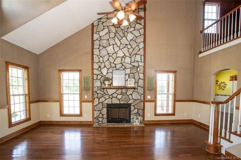 122 Barrier Farms Road Midland, NC 28107 - Photo 6 of 33 an empty room with wooden floor fireplace and windows