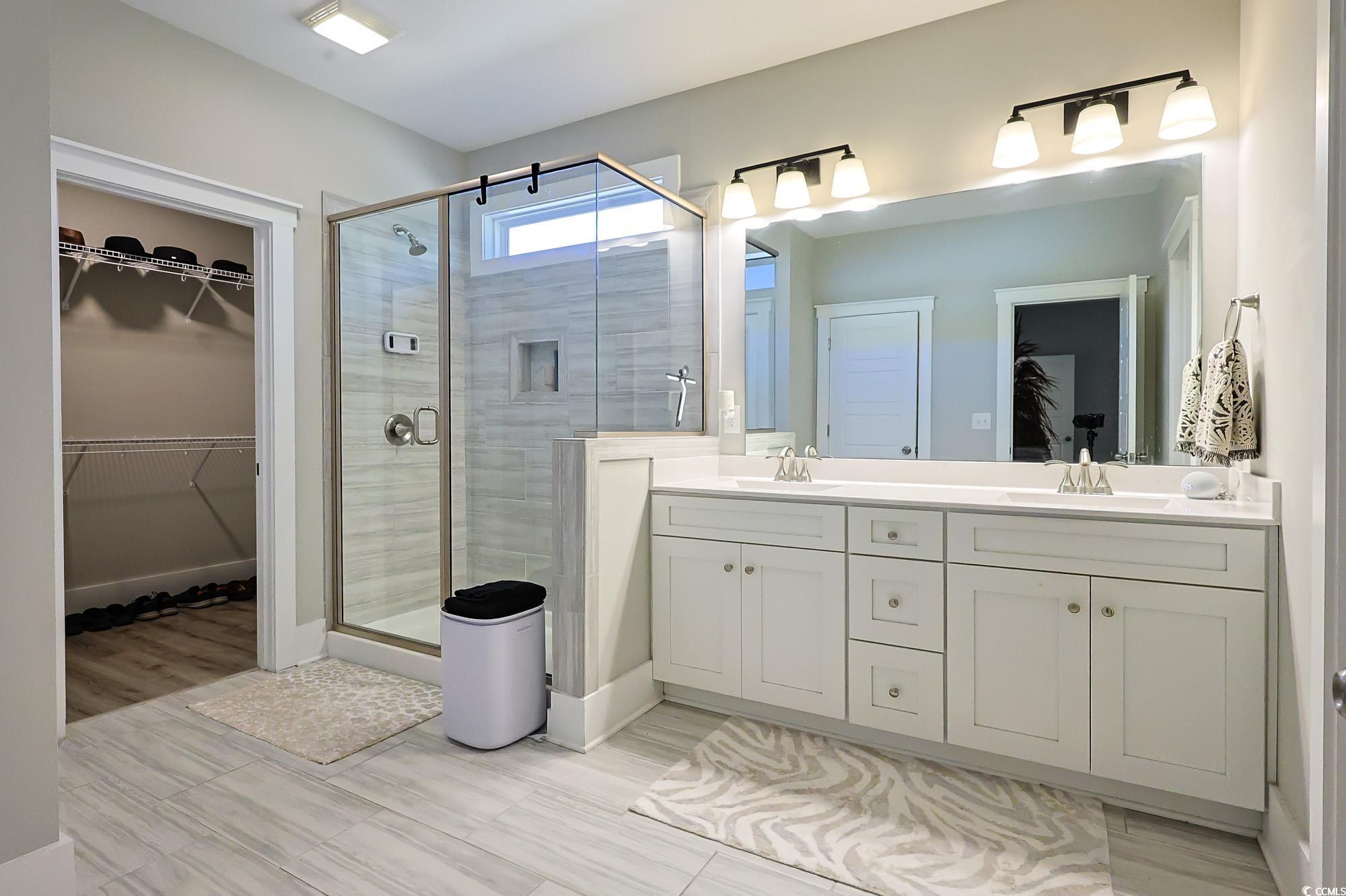 669 Pacific Commons Drive Surfside Beach, SC 29575 - Photo 12 of 36 Bathroom featuring a walk in closet, double vanity, and a shower stall