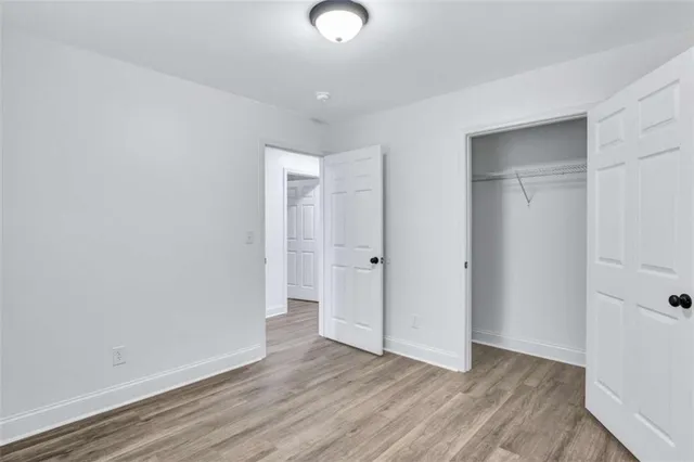 a view of an empty room with wooden floor and closet