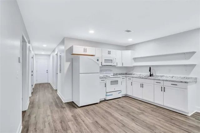 a kitchen with granite countertop white cabinets and white appliances