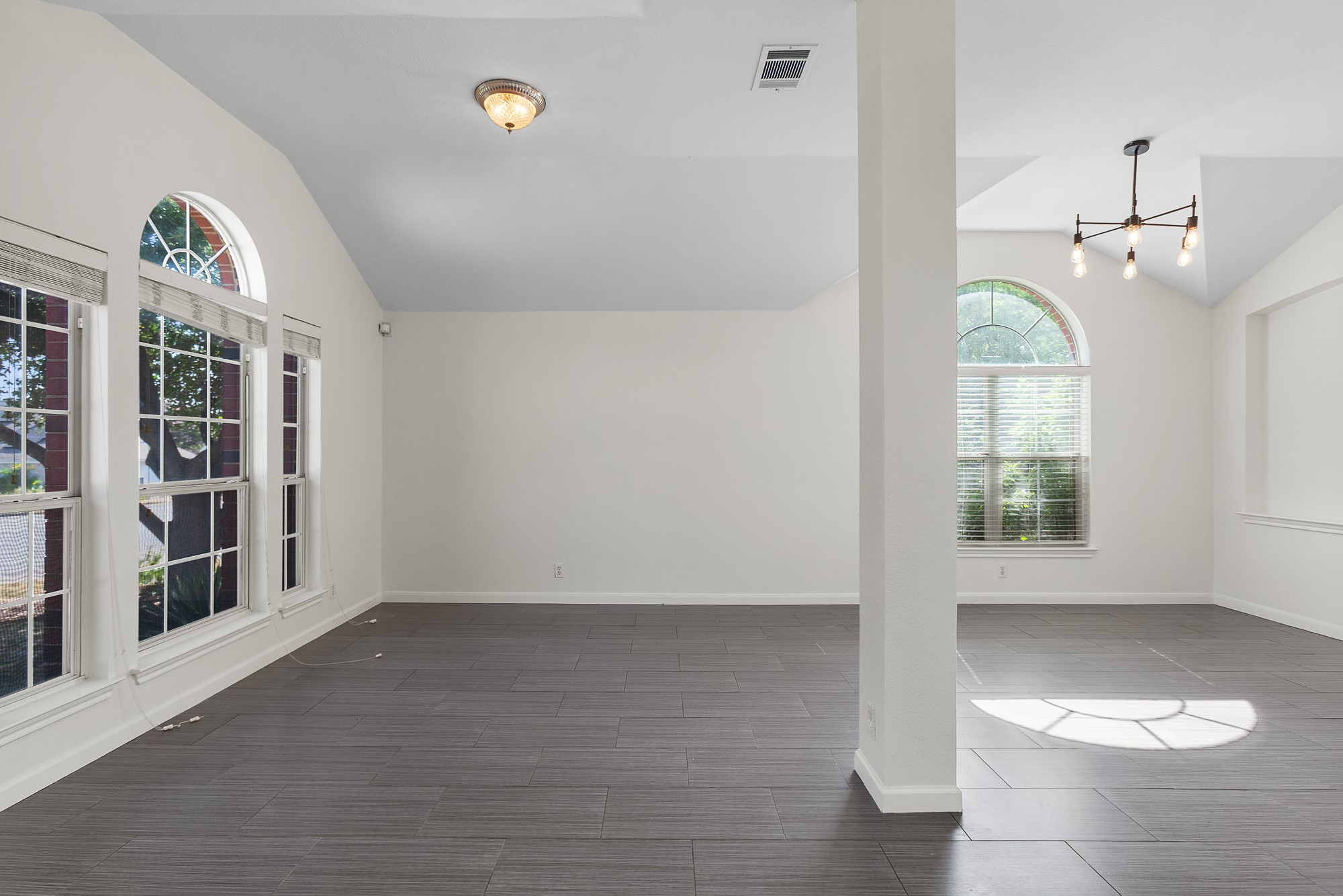 1201 Springbrook Road Pflugerville, TX 78660 - Photo 7 of 33 Natural illumination streams into this living area, featuring arched window accents and modern tile flooring.