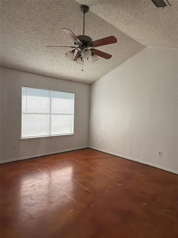 an empty room with a chandelier fan and windows