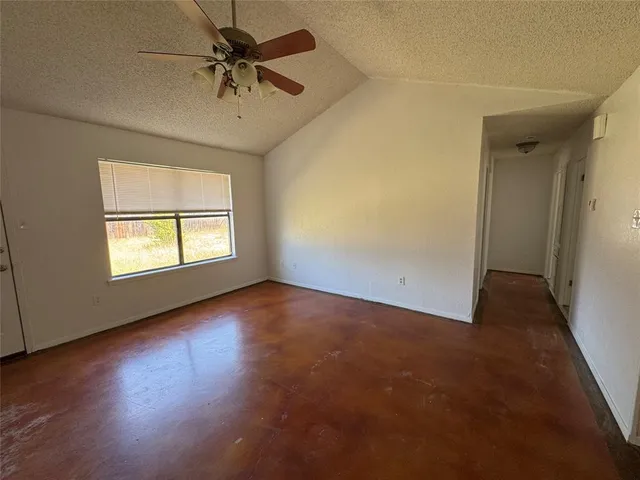 an empty room with a window and a ceiling fan