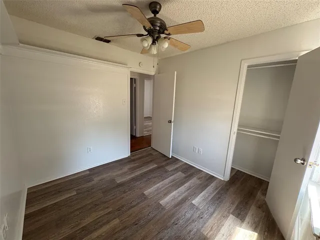 a view of a room with wooden floor and a ceiling fan