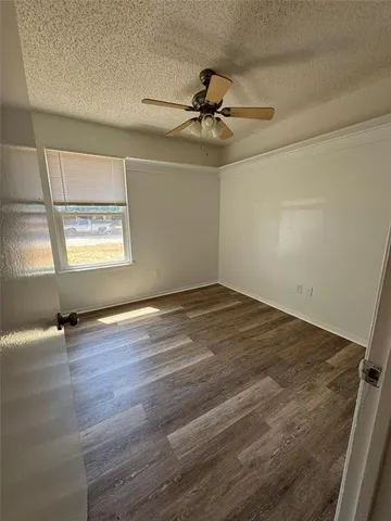 an empty room with wooden floor fan and windows