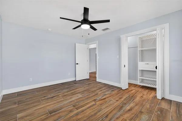 a view of empty room with wooden floor and ceiling fan