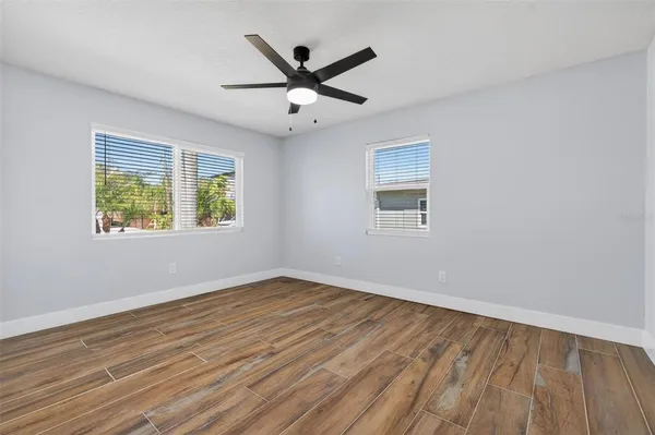 a view of empty room with wooden floor and fan
