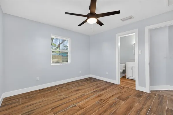 a view of empty room with wooden floor and fan