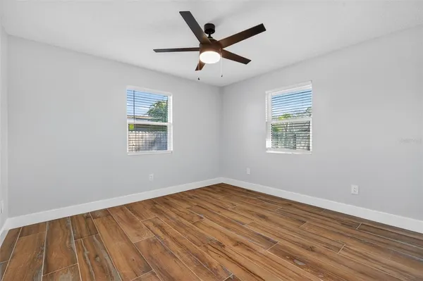 a view of empty room with wooden floor and fan
