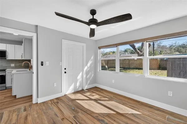 a view of empty room with wooden floor and fan