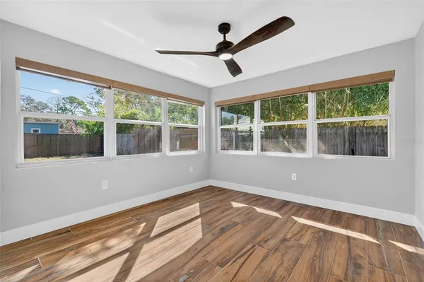 a view of empty room with wooden floor and fan