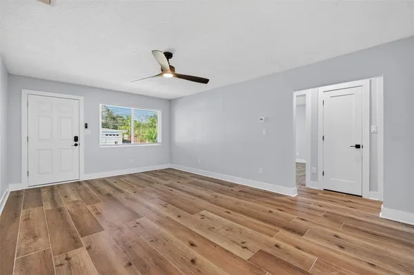 a view of an empty room with wooden floor and a window
