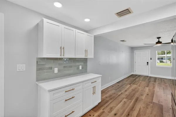 a view of a kitchen with white cabinets and wooden floor