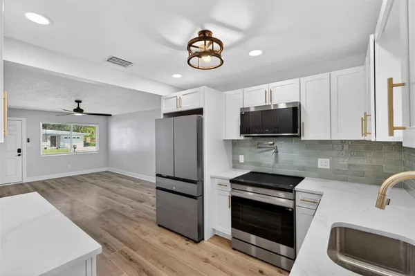 a kitchen with stainless steel appliances a stove a microwave and white cabinets